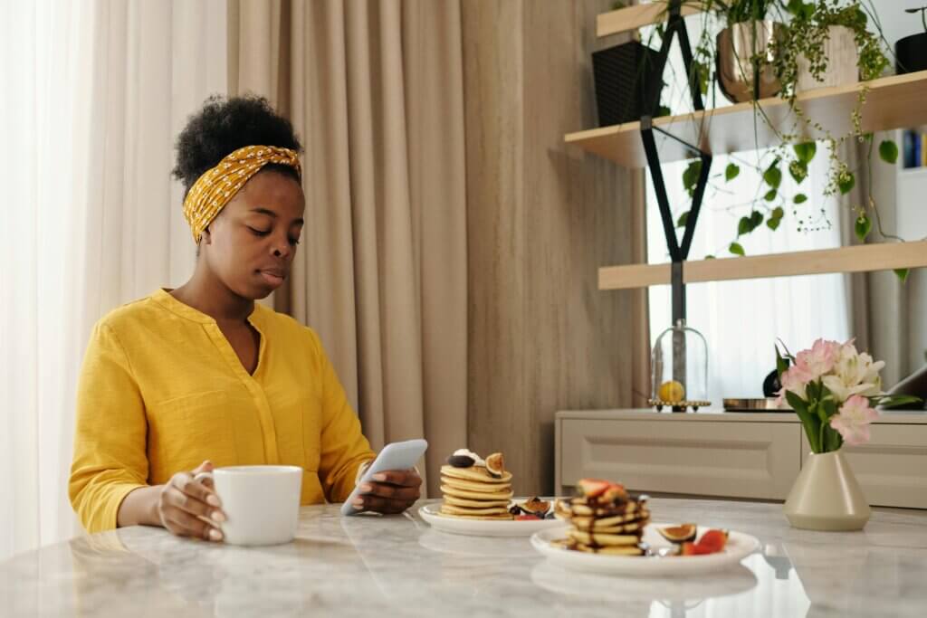 Black woman in yellow eating a quiet breakfast for introverted home design.